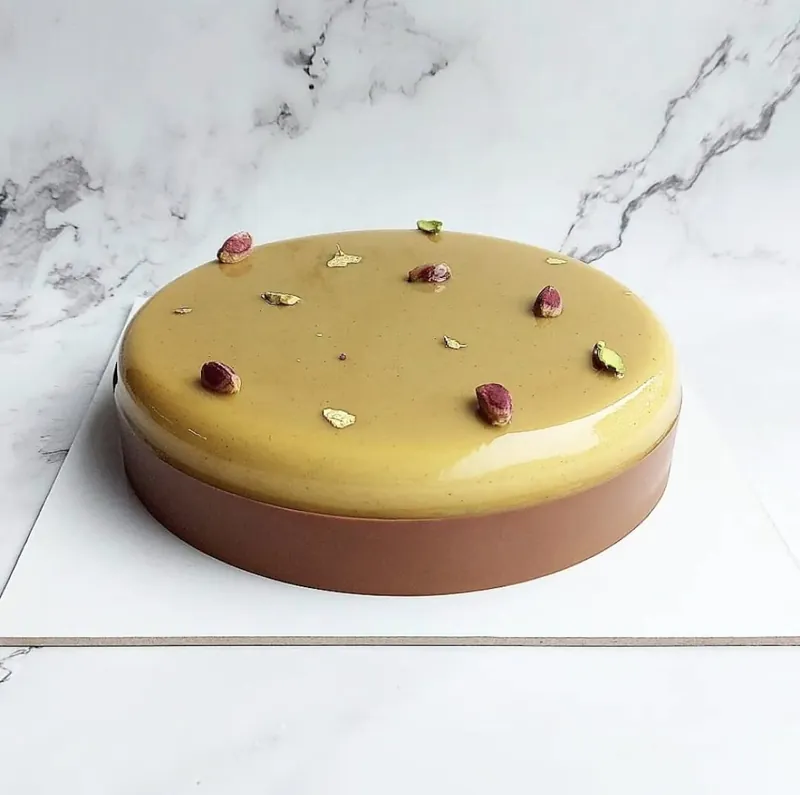 Torta semifreddo Alma, con glassa al pistacchio e granella di pistacchio in superficie.