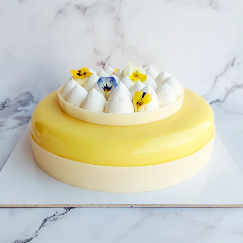 Torta semifreddo L’esotica, con meringhe a ciuffo e fiori eduli in superficie.