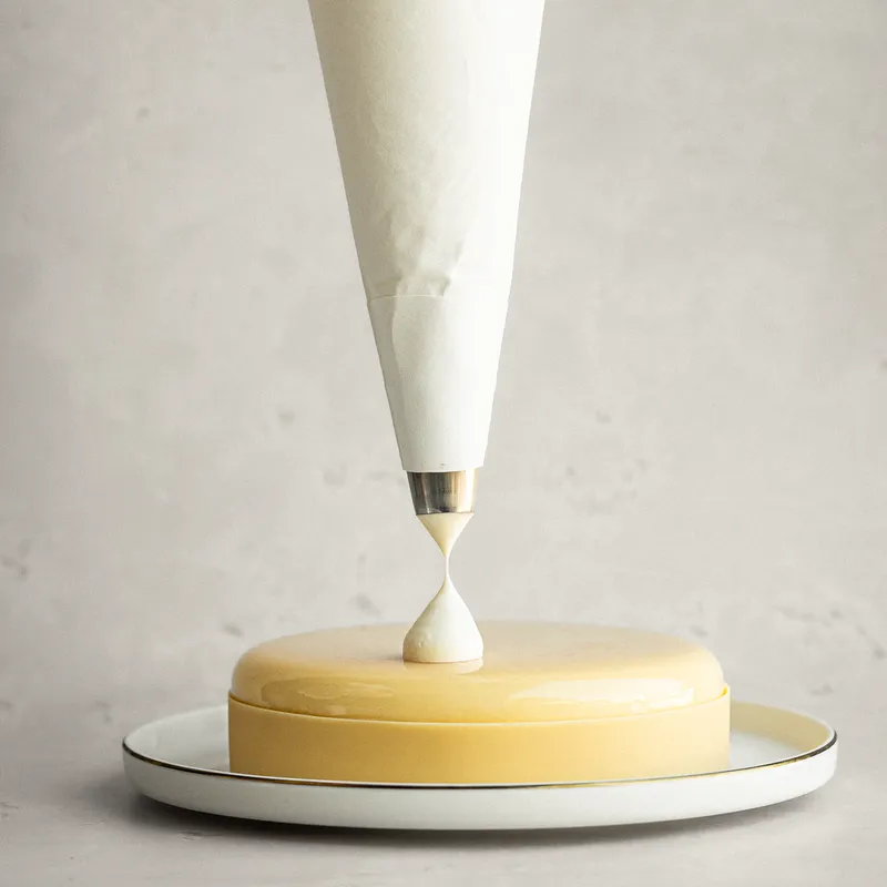 Glassa colata con la sac à poche su un semifreddo dalla superficie liscia e lucida.