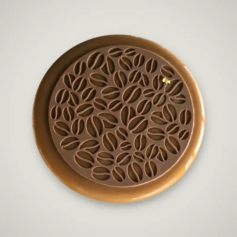 Vista dall'alto della torta Livia, con glassa lucida al caffè e un disco di cioccolato traforato a chicchi di caffè, con un fiocco di foglia d'oro.